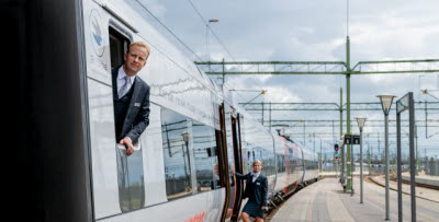 Lokförare och tågvärd lutar sig ut från ett Öresundståg