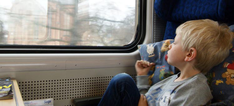 Pojke på tåg som kollar ut genom tågfönstret